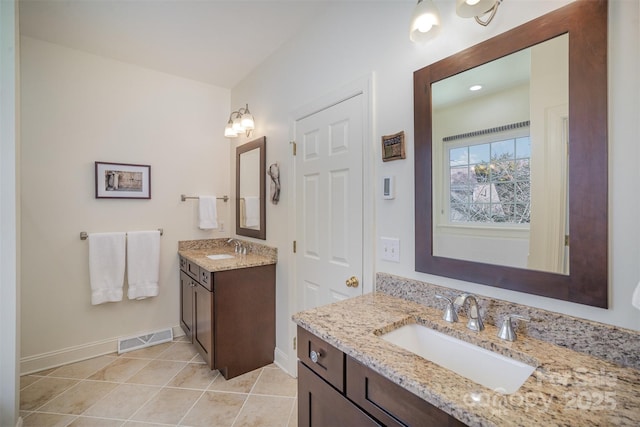 bathroom with a sink, baseboards, two vanities, and visible vents