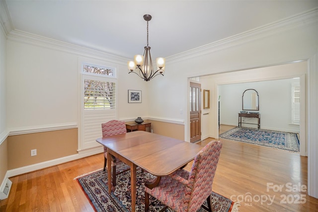 dining space featuring visible vents, crown molding, baseboards, an inviting chandelier, and light wood-style flooring