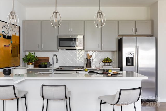 kitchen featuring decorative backsplash, light countertops, gray cabinetry, and stainless steel appliances