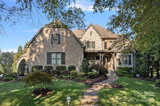 view of front facade featuring stone siding, brick siding, and a front lawn