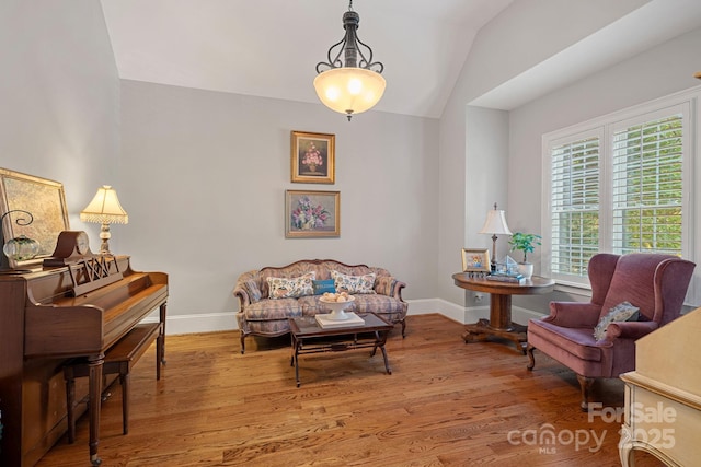 sitting room with baseboards, wood finished floors, and vaulted ceiling