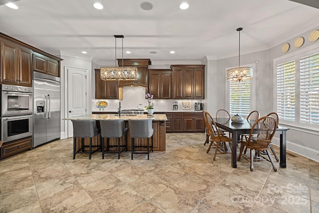 kitchen with a breakfast bar area, dark brown cabinets, appliances with stainless steel finishes, and a chandelier