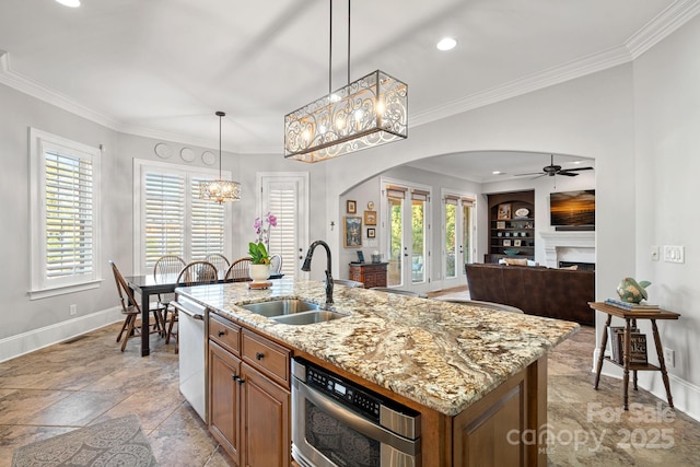 kitchen featuring a fireplace, arched walkways, ornamental molding, a sink, and stainless steel dishwasher