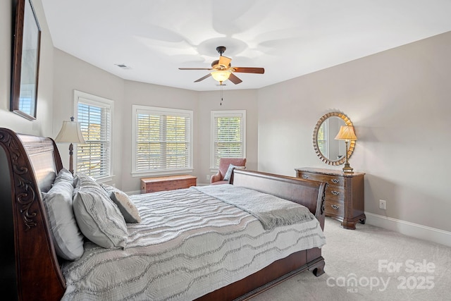 carpeted bedroom featuring visible vents, multiple windows, baseboards, and a ceiling fan