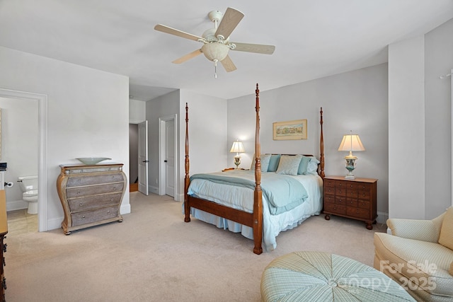 bedroom with ensuite bath, light colored carpet, baseboards, and ceiling fan