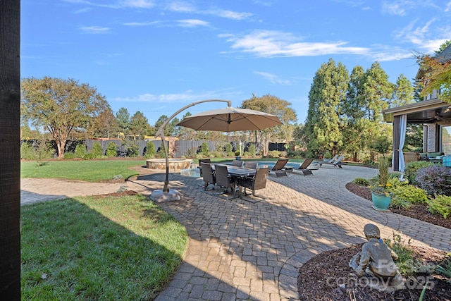 view of yard with outdoor dining space, a patio, a fenced backyard, and a pool with connected hot tub