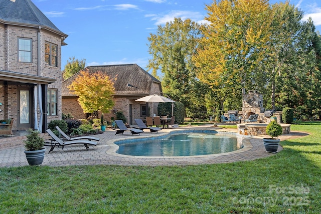 view of pool with a yard, a patio, and an outdoor fireplace