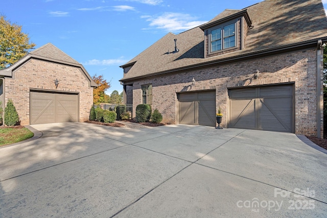 view of side of home featuring a garage, brick siding, and roof with shingles