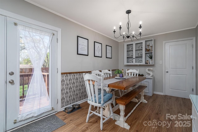 dining area with crown molding, a notable chandelier, wood finished floors, and baseboards