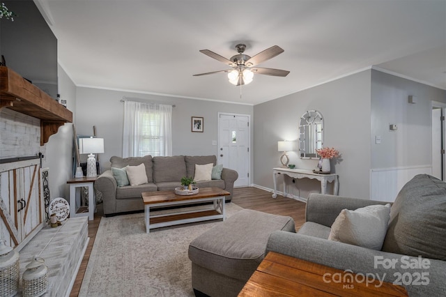 living area with ceiling fan, baseboards, wood finished floors, and crown molding