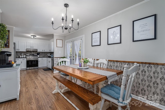 dining room with french doors, a chandelier, crown molding, and light wood finished floors