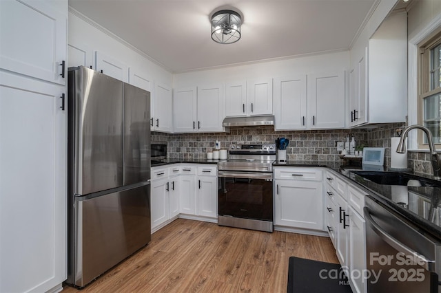 kitchen featuring under cabinet range hood, a sink, white cabinetry, light wood-style floors, and appliances with stainless steel finishes