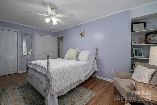 bedroom with two closets, ornamental molding, a ceiling fan, wood finished floors, and baseboards