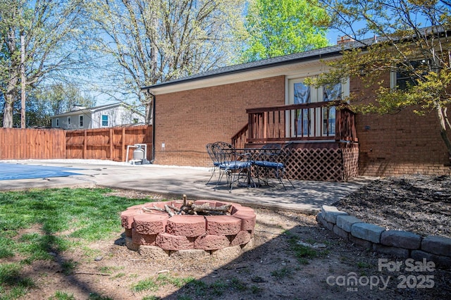 rear view of property with a patio area, fence, brick siding, and a fire pit