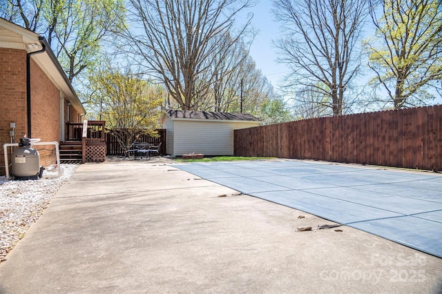 view of pool with a patio, an outbuilding, a wooden deck, a fenced backyard, and a storage unit