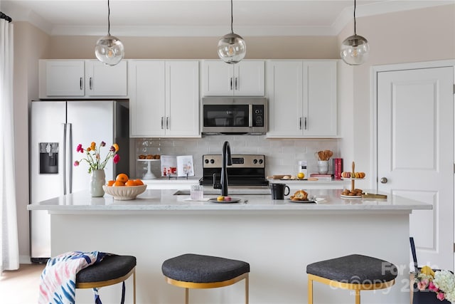 kitchen featuring decorative backsplash, appliances with stainless steel finishes, and a breakfast bar