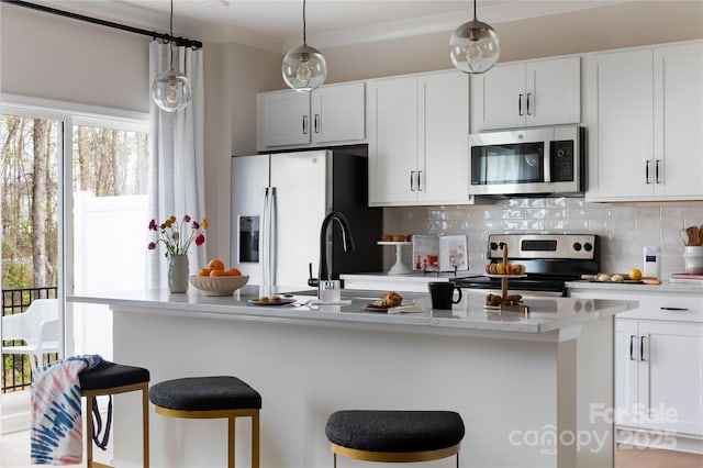 kitchen with decorative backsplash, light countertops, a breakfast bar area, and stainless steel appliances