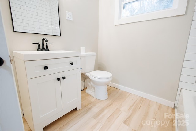 bathroom featuring vanity, toilet, wood finished floors, and baseboards