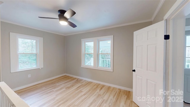 spare room with light wood-type flooring, plenty of natural light, baseboards, and ornamental molding