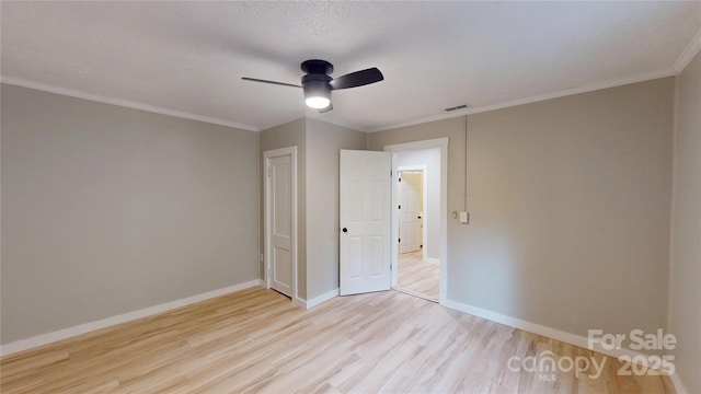 unfurnished bedroom with light wood-type flooring, visible vents, baseboards, and ornamental molding