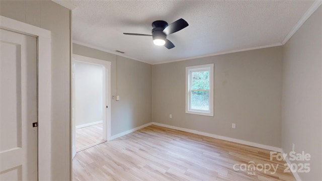 empty room with a ceiling fan, a textured ceiling, light wood-style flooring, and crown molding