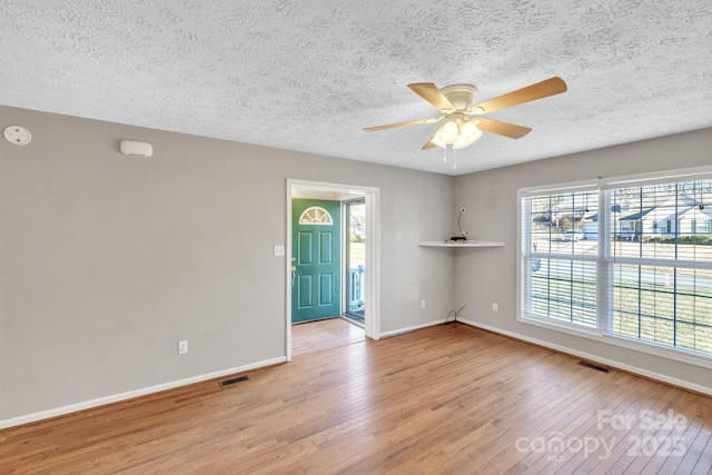 empty room featuring visible vents, plenty of natural light, and light wood-type flooring