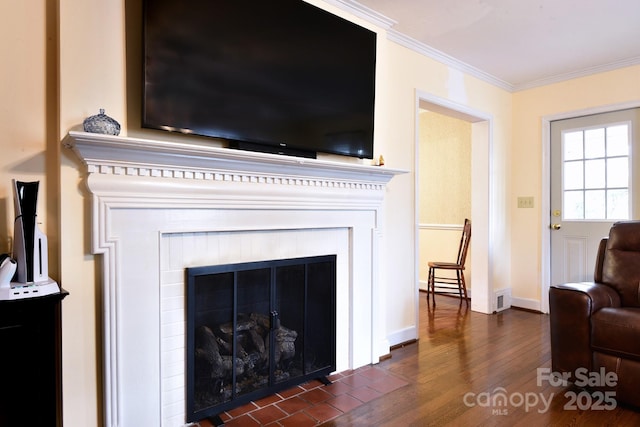 room details with visible vents, baseboards, a fireplace with flush hearth, ornamental molding, and wood finished floors