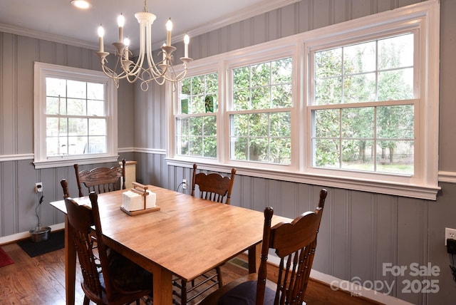 dining room with an inviting chandelier, dark wood finished floors, crown molding, and a decorative wall