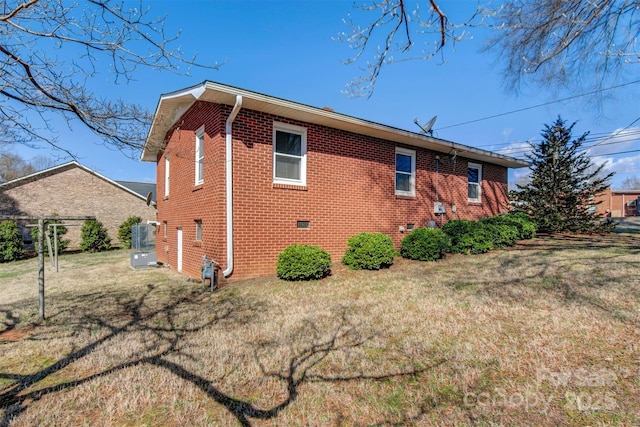 view of home's exterior with a lawn, brick siding, and crawl space