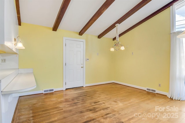 interior space featuring visible vents, vaulted ceiling with beams, baseboards, and wood finished floors