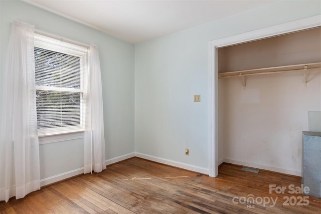 unfurnished bedroom with hardwood / wood-style floors, baseboards, and a closet