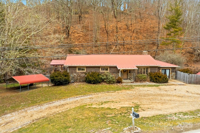 view of front of house featuring a front yard, fence, stone siding, and metal roof