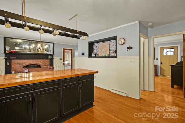 bar featuring light wood finished floors, baseboard heating, a fireplace, and ornamental molding