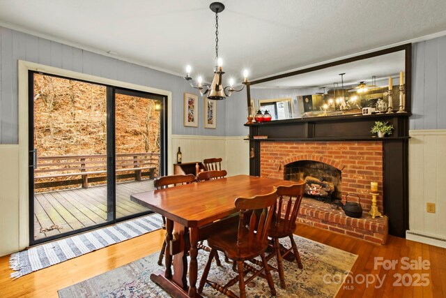 dining room featuring crown molding, a fireplace, a baseboard heating unit, and wood finished floors