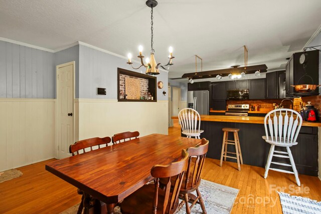 dining space with crown molding and light wood-style floors