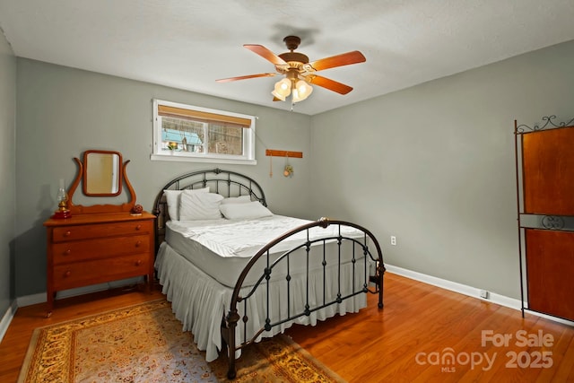 bedroom featuring a ceiling fan, wood finished floors, and baseboards