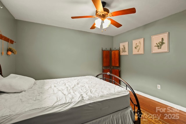 bedroom featuring ceiling fan, baseboards, and wood finished floors