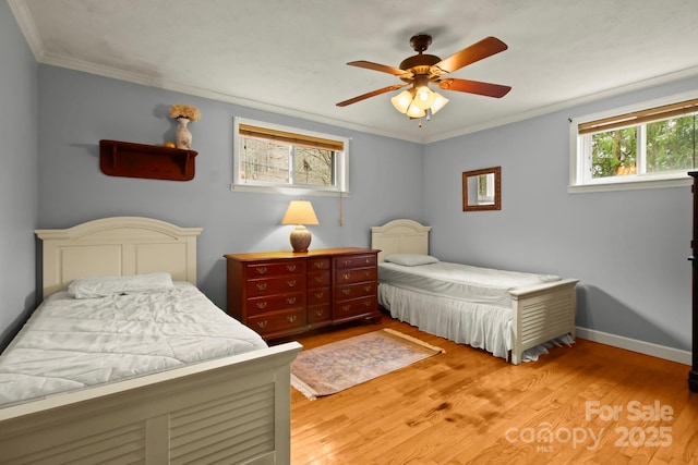 bedroom with a ceiling fan, crown molding, baseboards, and wood finished floors