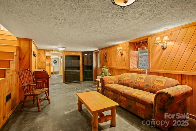 living area with wooden walls, concrete flooring, and a textured ceiling