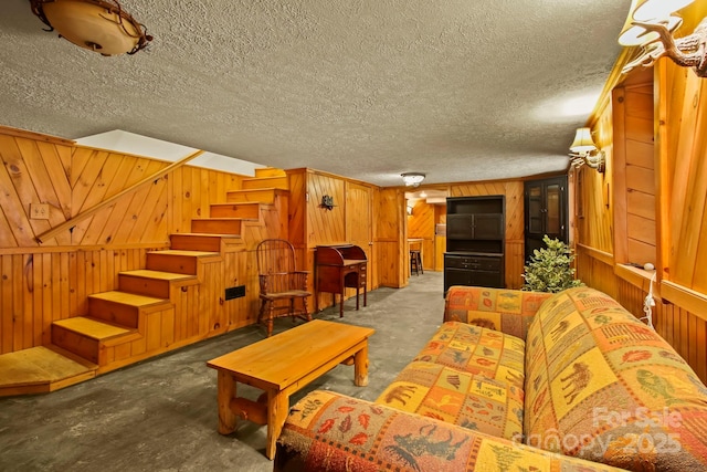 living room with stairway, a textured ceiling, and wooden walls