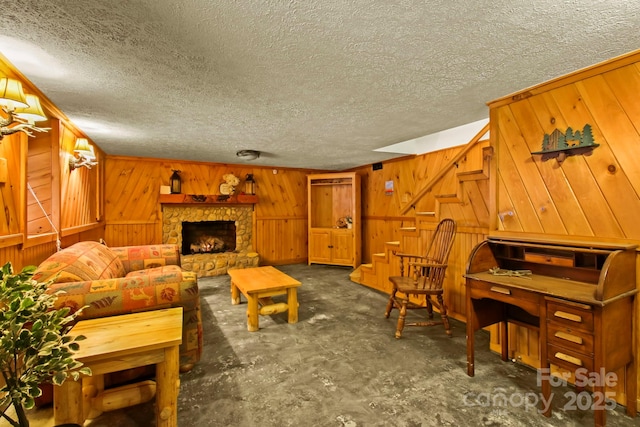 living area with wood walls, a fireplace, a textured ceiling, and stairs