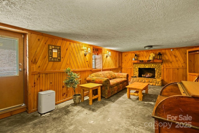 living room featuring a fireplace, a textured ceiling, and unfinished concrete floors