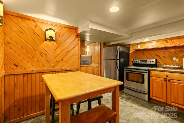 kitchen with wood walls, stainless steel appliances, and brown cabinets