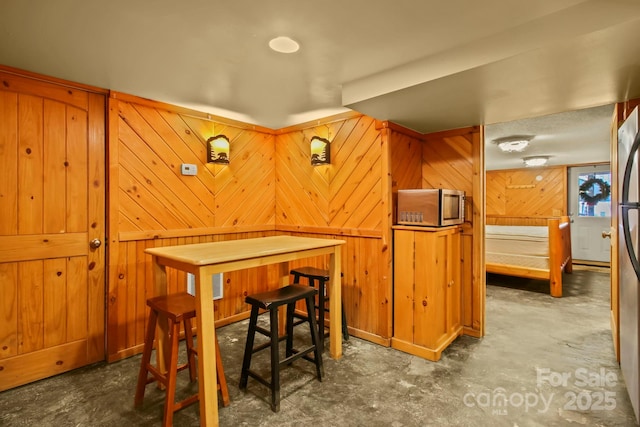 dining area with wooden walls and unfinished concrete flooring