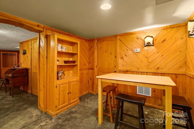 bar with wooden walls, visible vents, and a textured ceiling