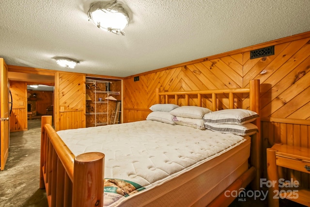 bedroom featuring a textured ceiling and wooden walls