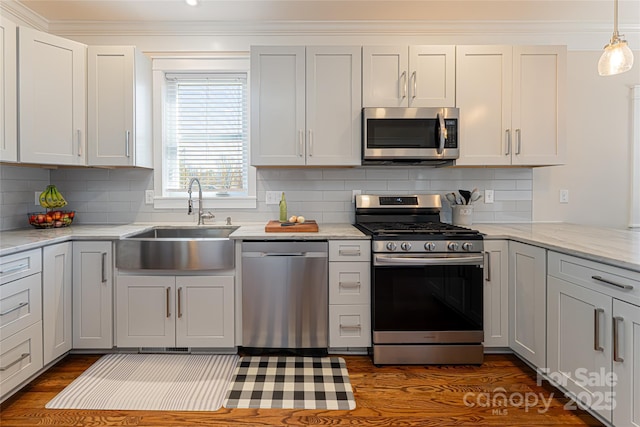 kitchen featuring backsplash, ornamental molding, stainless steel appliances, and a sink