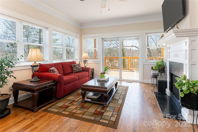 sunroom / solarium featuring plenty of natural light, visible vents, a fireplace with flush hearth, and ceiling fan