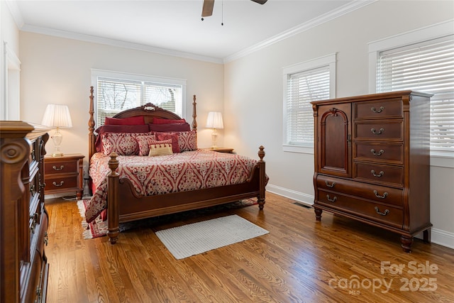 bedroom featuring visible vents, baseboards, wood finished floors, and ornamental molding