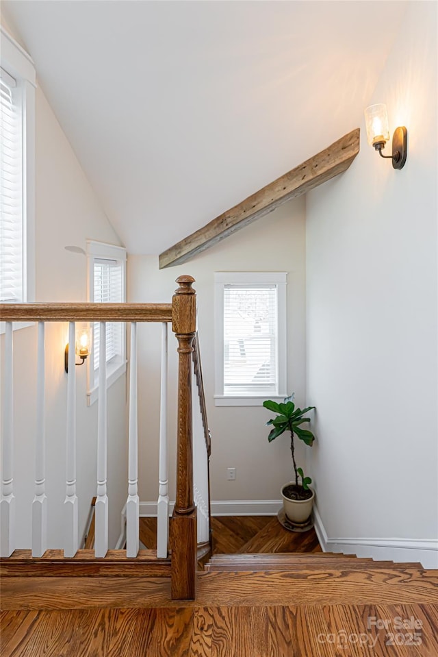 staircase featuring baseboards, lofted ceiling, and wood finished floors